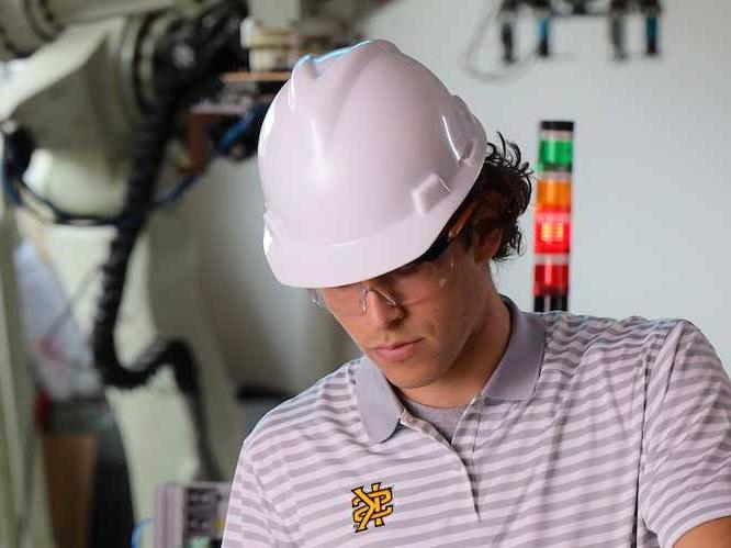 Student has goggles and a hard hat on focusing on a project